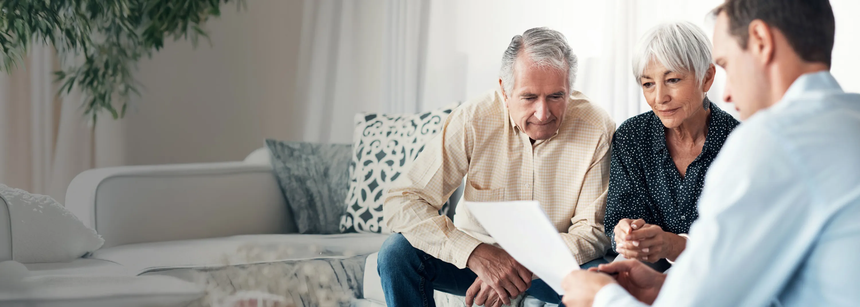 Un couple et un notaire sont assis sur un canapé et examinent un testament.