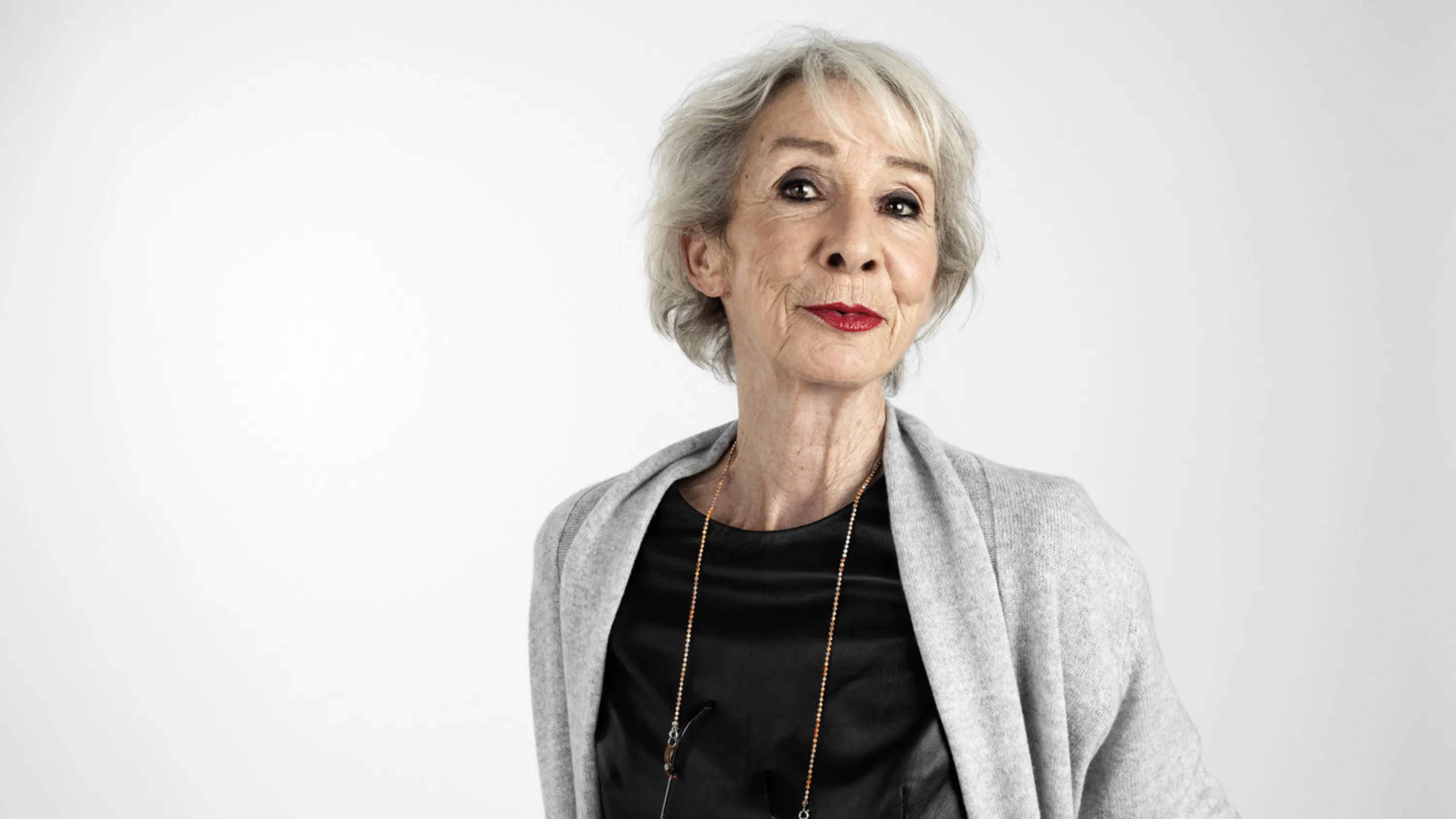 Eine ältere Dame schaut zufrieden in die Kamera.